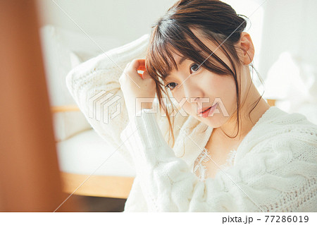 髪の毛をまとめる若い女性 77286019