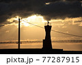 明石海峡大橋と朝日をバックに灯台シルエット 77287915