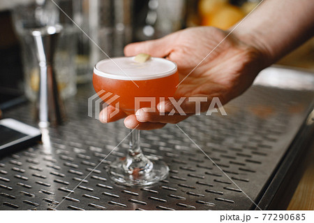 Red cocktail in a glass on a barstique 77290685