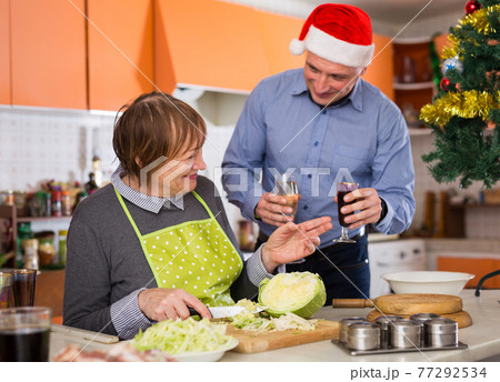 Senior woman cutting xmas salad, man with champagne 77292534