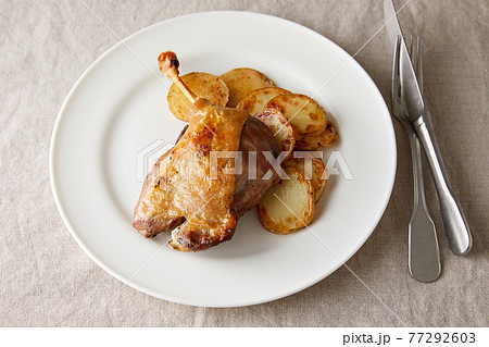 シンプルな白いお皿に盛られた鴨のコンフィと付け合せのジャガイモのロースト シンプルな白いお皿に盛られた鴨のコンフィと付け合せのジャガイモのロースト 77292603