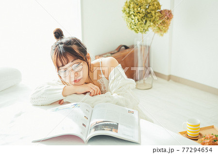 雑誌を読むメガネをかけた女の子 77294654