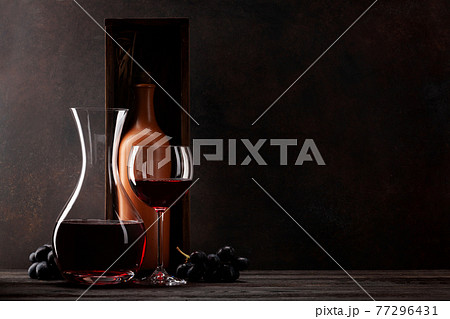 Decanter with red wine, wine bottle in box, grapes and wineglass Decanter with red wine, wine bottle in box, grapes and wineglass 77296431
