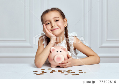 Little child girl with piggy bank at home Little child girl with piggy bank at home 77302816