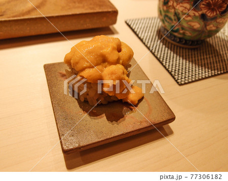 A piece of sea urchin (uni) sushi on a beautiful pottery at a high class sushi restaurant in Ginza, Tokyo, Japan. A piece of sea urchin (uni) sushi on a beautiful pottery at a high class sushi restaurant in Ginza, Tokyo, Japan. 77306182