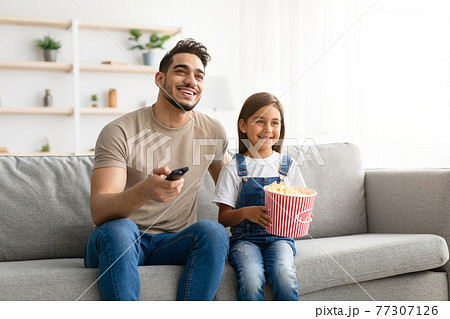 Happy young family watching television sitting on couch Happy young family watching television sitting on couch 77307126