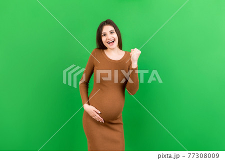 Young beautiful pregnant woman on isolated colored background celebrating surprised and amazed for success with arms raised and open eyes. Winner concept 77308009