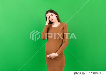 Beautiful young pregnant woman feeling head ache on colored background isolated. Stressed pregnant woman or mother problems Beautiful young pregnant woman feeling head ache on colored background isolated. Stressed pregnant woman or mother problems 77308010