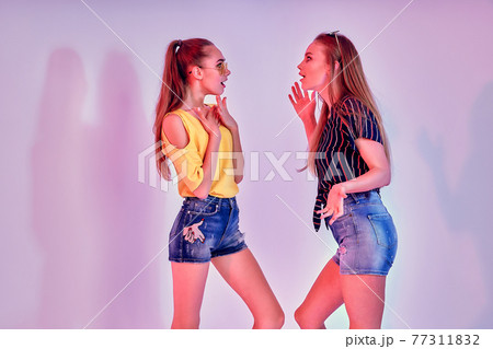 Two female teenagers in sunglasses and summer clothes posing in studio on white background Two female teenagers in sunglasses and summer clothes posing in studio on white background 77311832