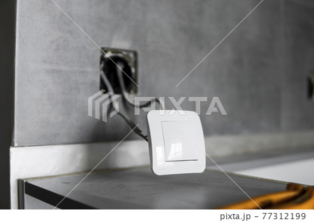 Repair or installation of a new light switch in the wall. Light switch connected via cables to a electricity in a home. 77312199