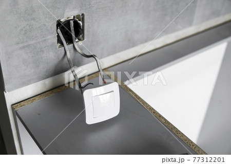 Repair or installation of a new light switch in the wall. Light switch connected via cables to a electricity in a home. 77312201