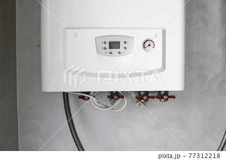 White modern home gas boiler mounted on a grey wall on a kitchen. Water heater. Water heating, ecology. White modern home gas boiler mounted on a grey wall on a kitchen. Water heater. Water heating, ecology. 77312218