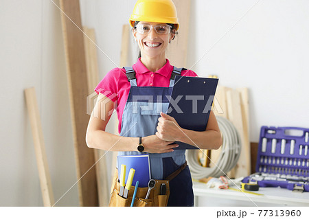 Smiling woman builder holds clipboard with documents in her hands 77313960