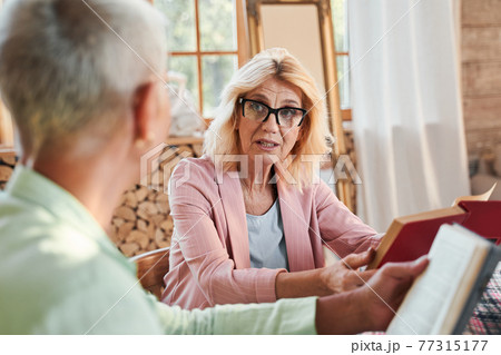 Woman discussing a book with her friend Woman discussing a book with her friend 77315177
