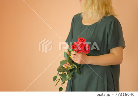 Portrait of young woman dressed in green dress holding bouquet of roses Portrait of young woman dressed in green dress holding bouquet of roses 77316046