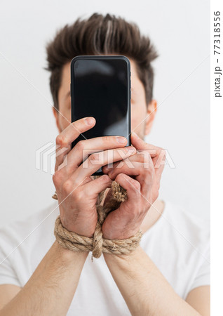 a person with his hands tied holding a smartphone, internet addiction, or social media addiction. 77318556