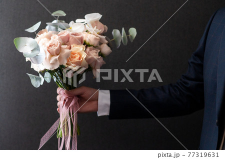 the groom gives a wedding bouquet to the bride. Bouquet in the hands of a man the groom gives a wedding bouquet to the bride. Bouquet in the hands of a man 77319631