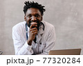 Handsome contented African American doctor working on a laptop. telemedicine 77320284