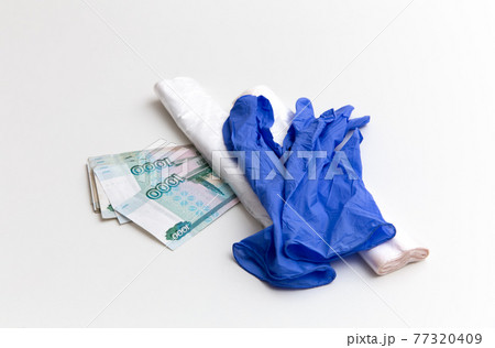 Plastic bags and blue gloves are on the ruble banknotes on the white background. Package Plastic bags and blue gloves are on the ruble banknotes on the white background. Package 77320409