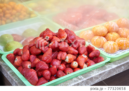 Chilled fruits lie in tray on store counter surrounded by fog. Chilled fruits lie in tray on store counter surrounded by fog. 77320658