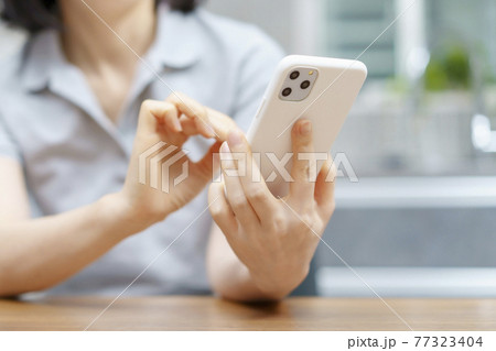 室内でスマートフォンを操作する女性 77323404