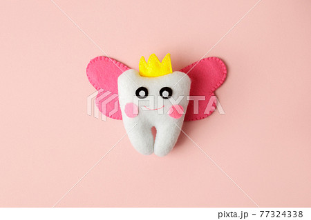 Cute toy for Tooth Fairy Day as funny smiling cartoon character of tooth fairy with crown, wings on pink background, copy space flyer, concept children milk toothless, funny toy, handmade felt diy Cute toy for Tooth Fairy Day as funny smiling cartoon character of tooth fairy with crown, wings on pink background, copy space flyer, concept children milk toothless, funny toy, handmade felt diy 77324338