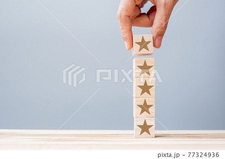 Hand holding wooden blocks with the star symbol. Customer reviews, feedback, rating, ranking and service concept. 77324936