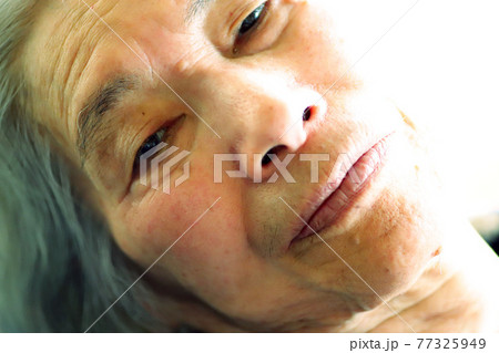 介護ベッドに横たわるシニア女性のクローズアップ 介護ベッドに横たわるシニア女性のクローズアップ 77325949