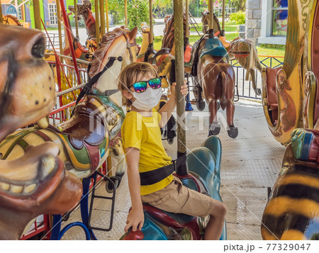Boy wearing a medical mask during COVID-19 coronavirus at an amusement park 77329047