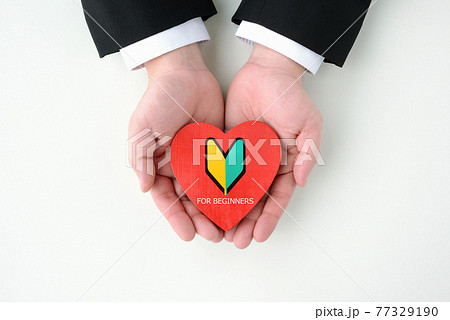 初心者マークの付いたハートのオブジェを持つビジネスマンの手の写真素材