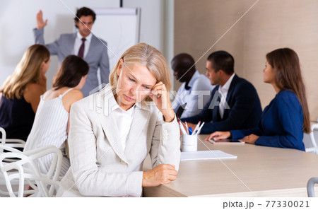 Frustrated mature woman on background with boss scolding subordinates Frustrated mature woman on background with boss scolding subordinates 77330021