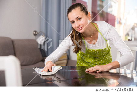 Woman with rag cleaning kitchen table 77330383