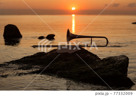wind instrument pipe lies near the sea on a stone on the background of the red dawn wind instrument pipe lies near the sea on a stone on the background of the red dawn 77332009