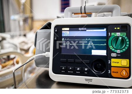 Monitor screen for medical defibrillator or emergency heart pump,showing vital signs,heart rate,slow beating pulse of a dying coma patient in a hospital ICU room or deaths from Coronavirus COVID-19 77332373