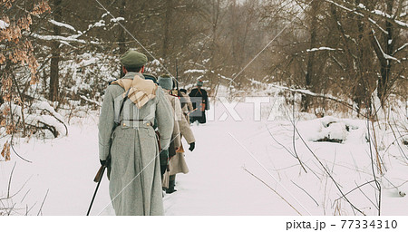Men Dressed As White Guard Soldiers Of Imperial Russian Army In Russian Civil War Times Marching Through Snowy Winter Forest. Historical Reenactment 1917-1922. 77334310