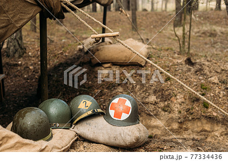 Metal Helmets Of United States Army Infantry Soldier At World War II. Helmets Near Camping Tent In Forest Camp Metal Helmets Of United States Army Infantry Soldier At World War II. Helmets Near Camping Tent In Forest Camp 77334436