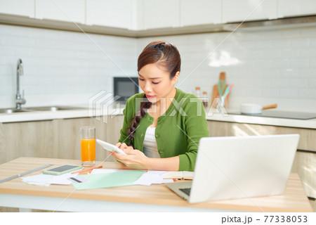 An attractive young housewife grimly considers spending this month and is under stress when checking accounts. An attractive young housewife grimly considers spending this month and is under stress when checking accounts. 77338053