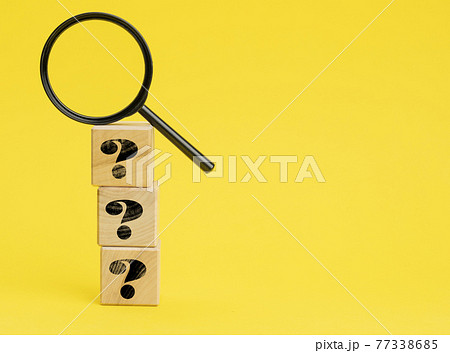 wooden cubes with question marks and a magnifying glass on a yellow background. The concept of finding answers to unknown questions wooden cubes with question marks and a magnifying glass on a yellow background. The concept of finding answers to unknown questions 77338685