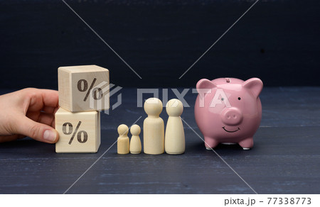 wooden family figurines and  pink ceramic piggy bank on blue background, saving concept 77338773