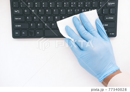 hand in blue rubber gloves and white tissue disinfecting keyboard hand in blue rubber gloves and white tissue disinfecting keyboard 77340028