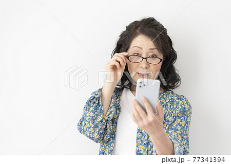 老眼鏡をかけてスマホをみるシニア女性 77341394