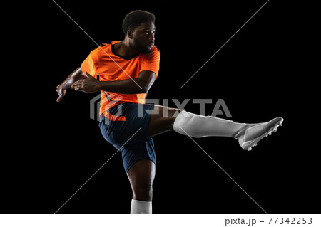 African-american football player playing isolated on black background. Concept of sport. African-american football player playing isolated on black background. Concept of sport. 77342253