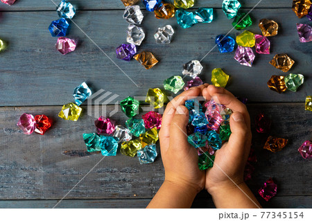 カラフルなアクリルストーンで遊ぶ子供の手 77345154