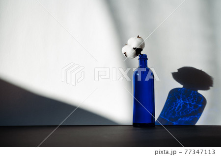 Blue glass bottle with a cotton flower 77347113