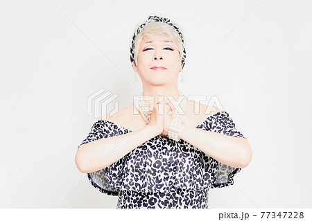 白背景の前に立って、お願いのジェスチャーをするドラァグクイーン 77347228