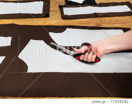 hand cuts brown fabric by scissors with pattern hand cuts brown fabric by scissors with pattern 77348282