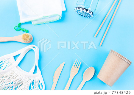 Zero waste or plastic free concept, wooden and paper utensil, reusable bags and glass, on blue background, horizontal, top view, copy space 77348429