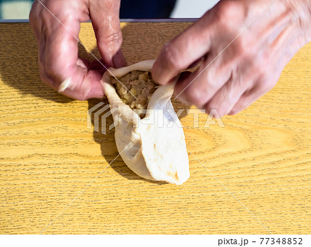female hands wrap filling in raw dough on table female hands wrap filling in raw dough on table 77348852