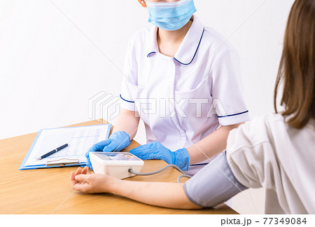 患者の血圧を測る看護師 77349084