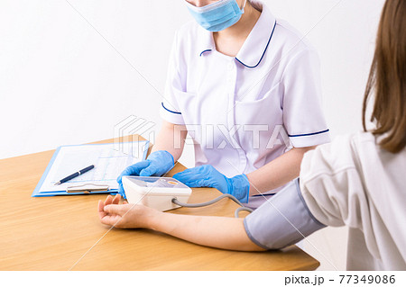 患者の血圧を測る看護師 77349086
